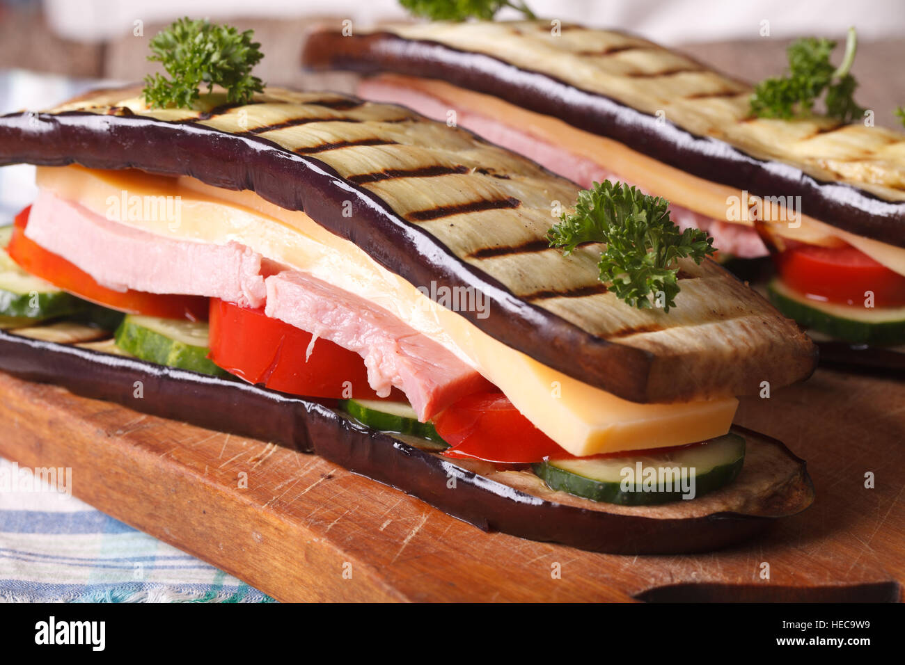 Delizioso e sano sandwich di melanzane con verdure fresche, prosciutto e formaggio close up orizzontale. Foto Stock