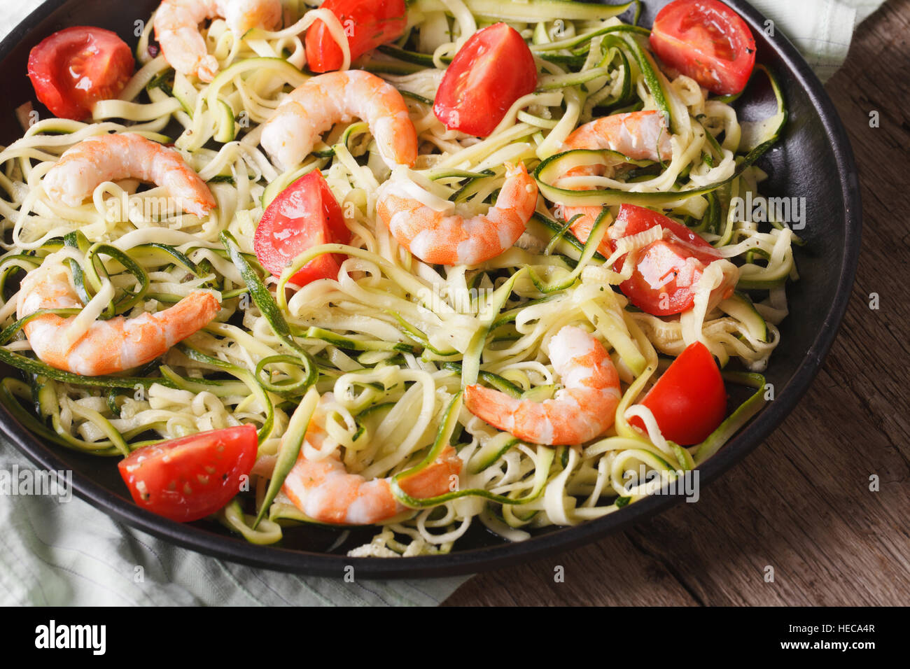 Alimenti dietetici: Zucchine pasta con gamberi e pomodoro su una piastra di close-up orizzontale. Foto Stock