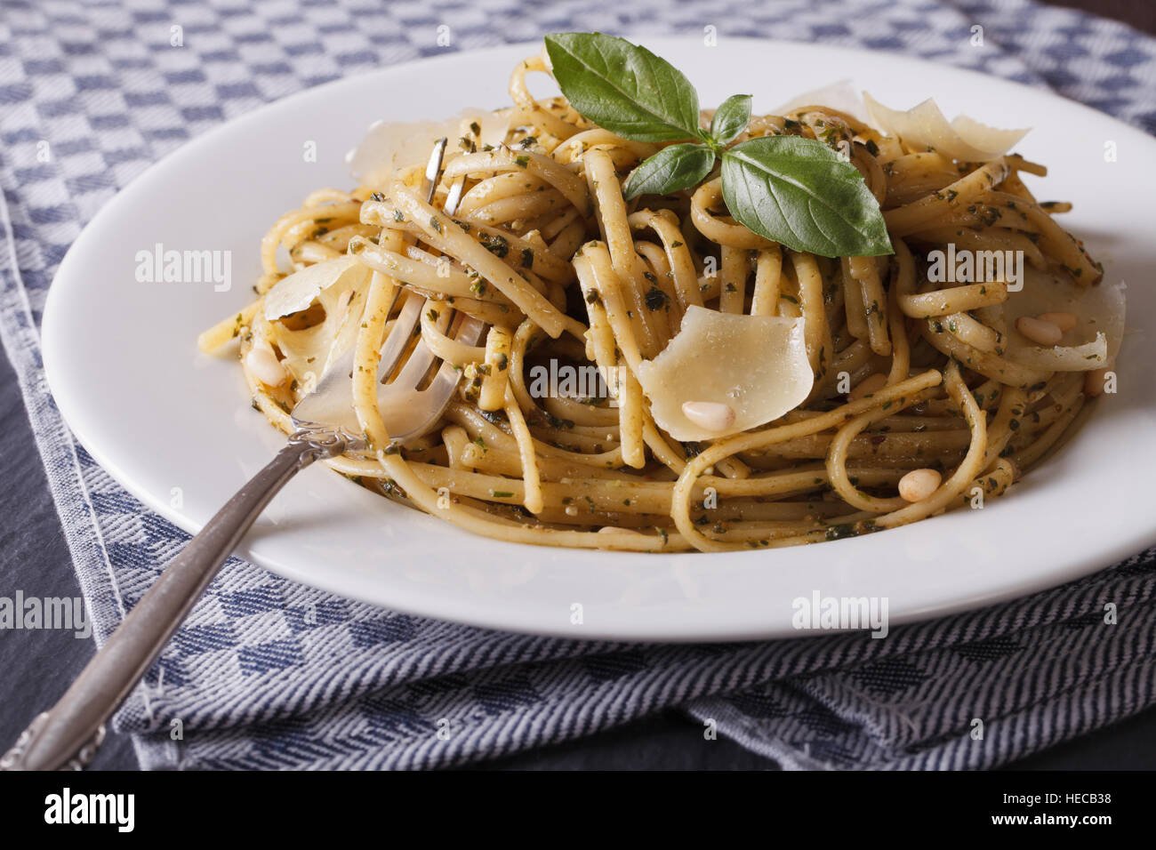 Pasta al pesto, pinoli e parmigiano close-up su una piastra bianca orizzontale. Foto Stock