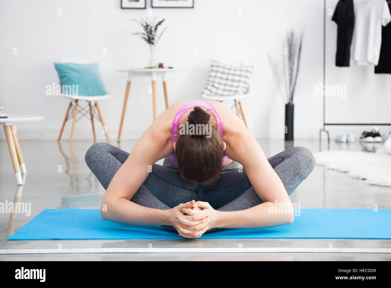 Giovane donna caucasica stretching e fare yoga a casa Foto Stock