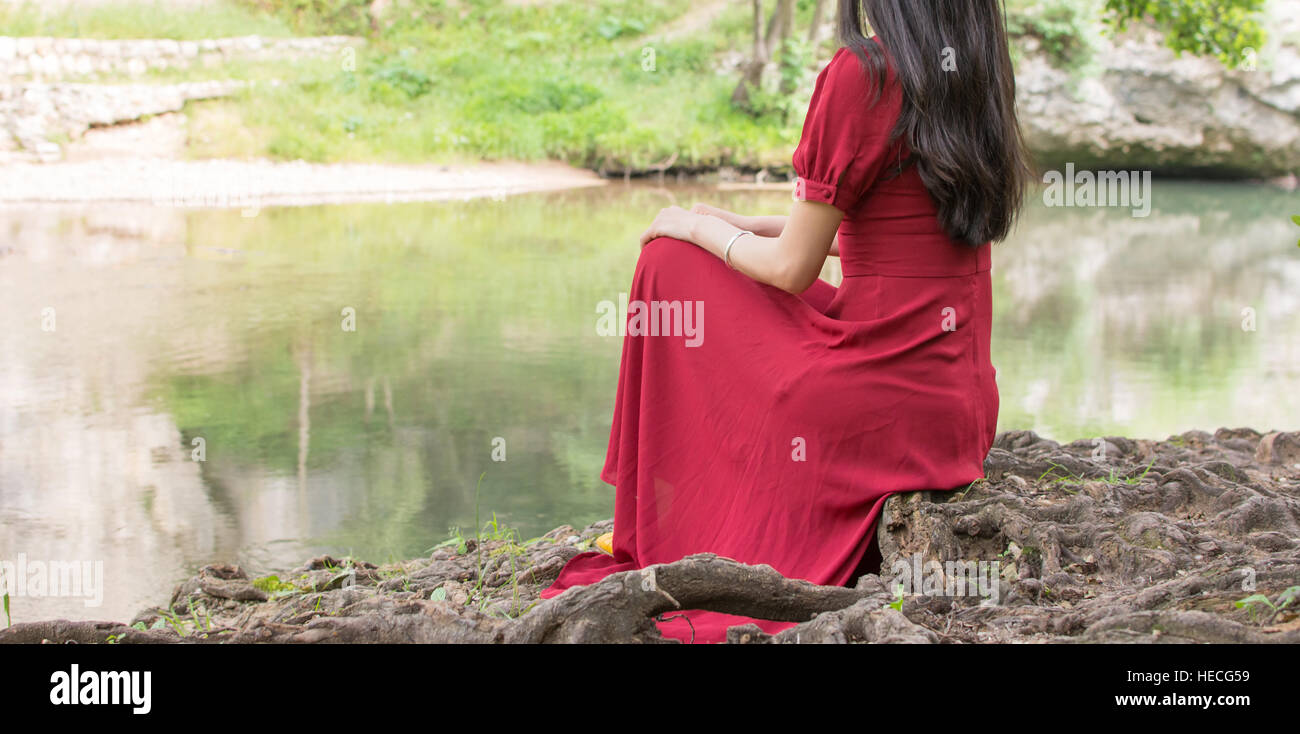 Moda donna seduta accanto a un fiume da soli Foto Stock
