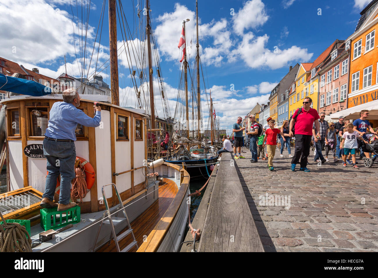 Un uomo pittura la sua barca lungo Nyhavn Canal, Copenhagen, Danimarca Foto Stock