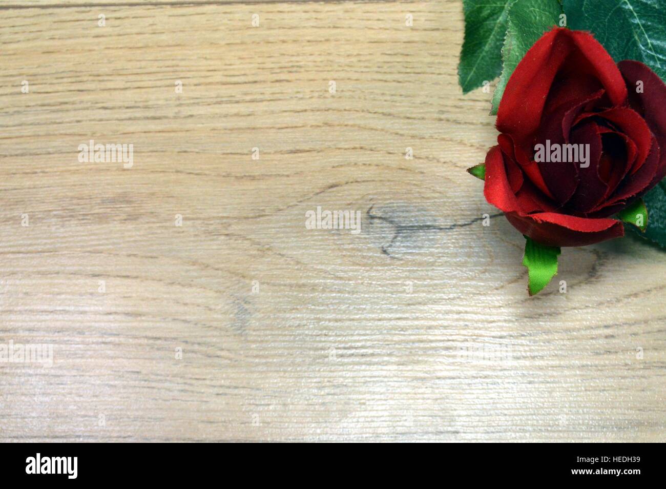 Red Rose con foglie di cuneo su un marrone Sfondo legno Foto Stock