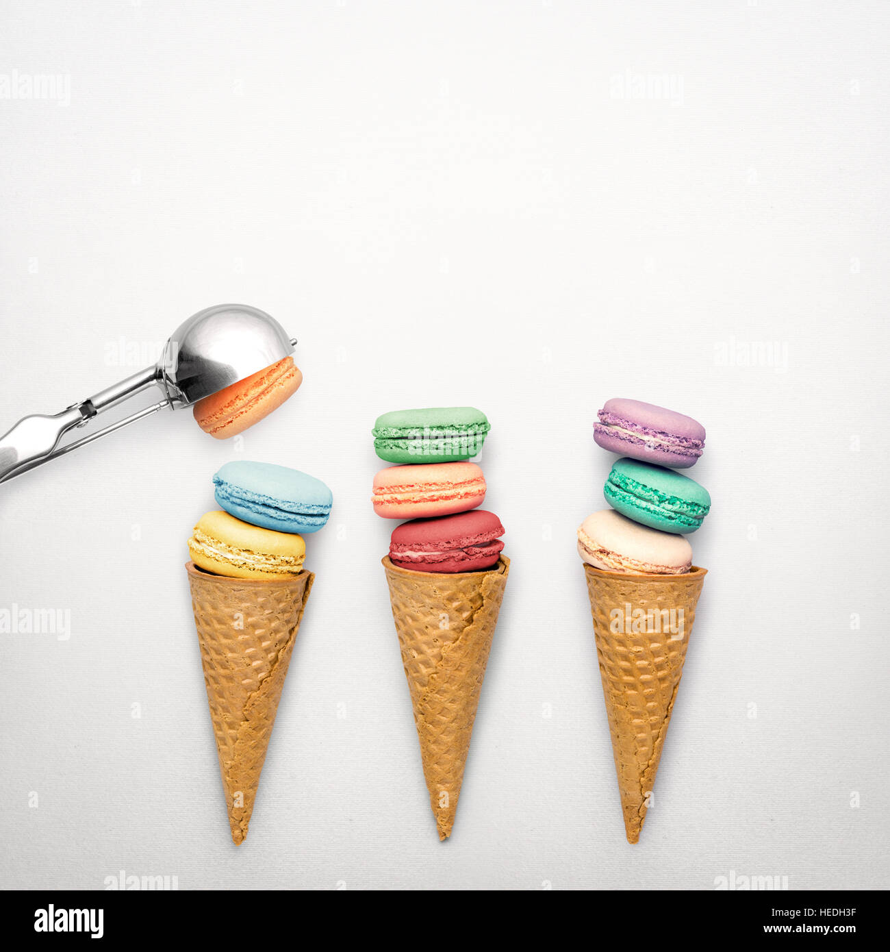 Creative ancora vita foto di tre coni di cialda con amaretti e cucchiaio su sfondo grigio. Foto Stock