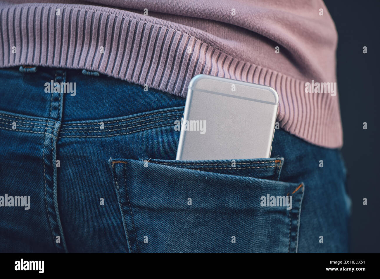 Donna con il nuovo smartphone in her blue jeans pantaloni tasca posteriore Foto Stock