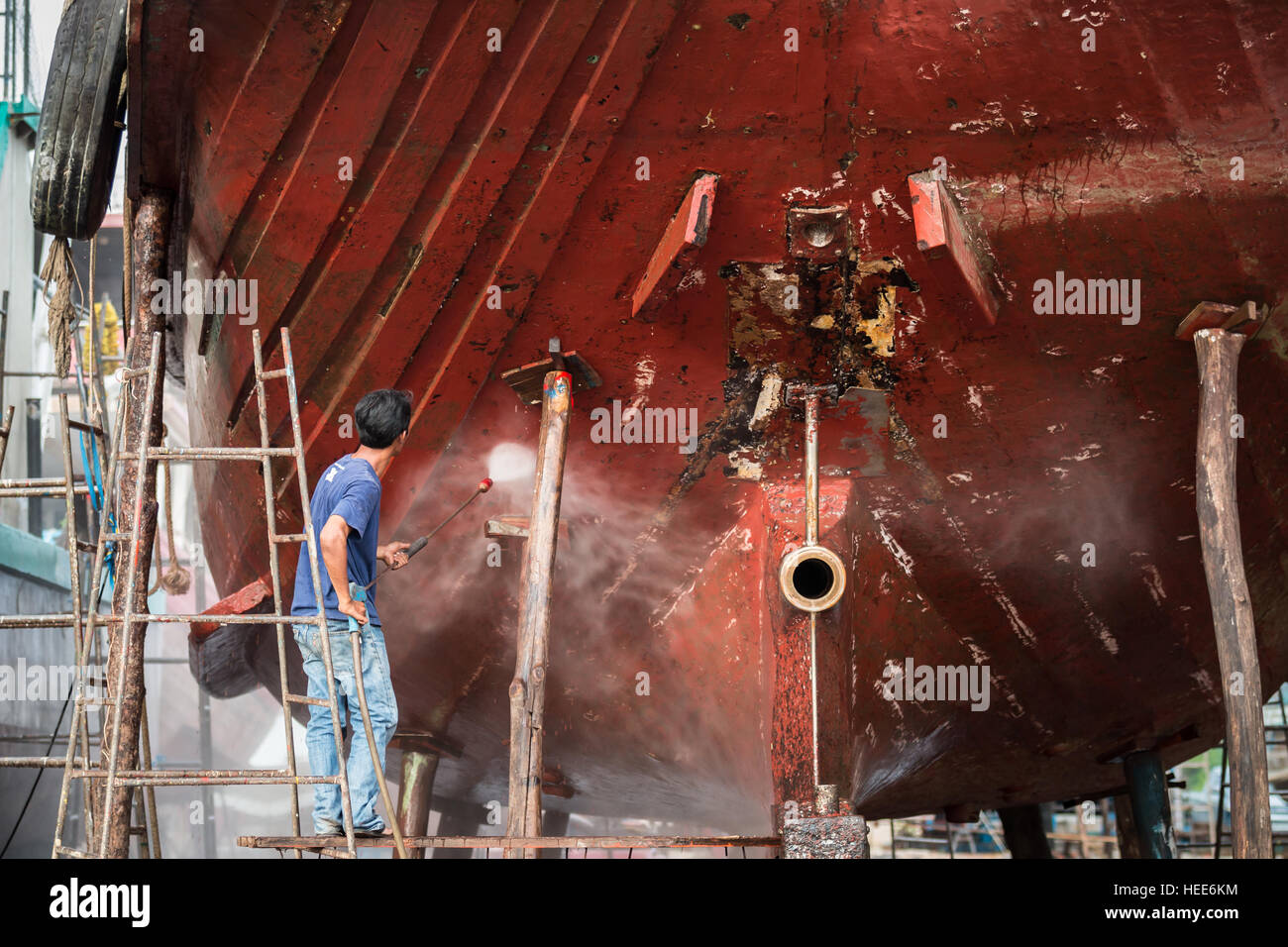 Un uomo che lavora sulla rondella di pressione per la pulizia scafo cirripedi antivegetativo e alghe marine al porto Foto Stock