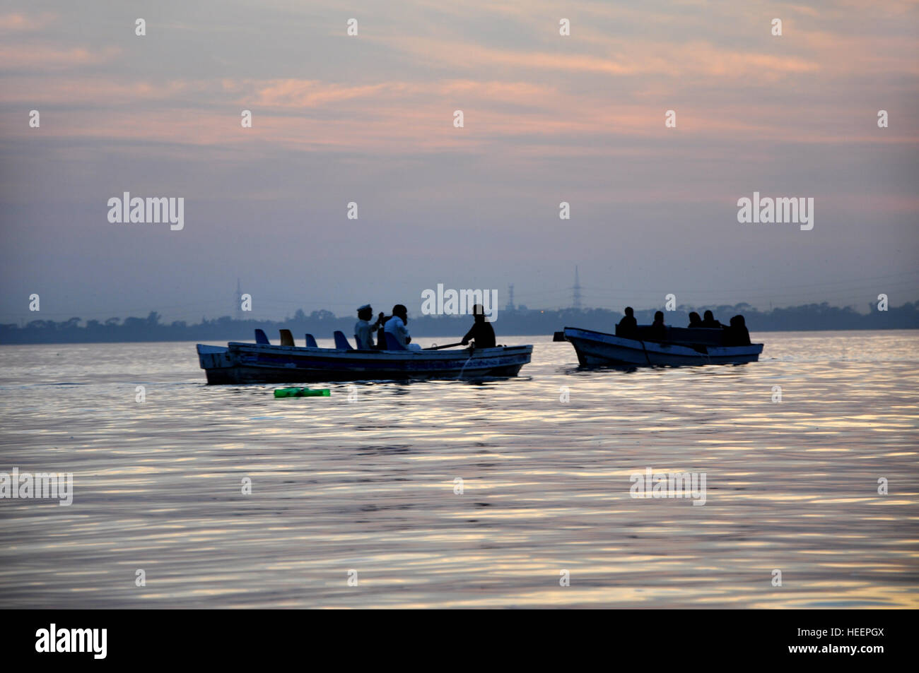 Persone che viaggiano su una barca in un lago al tramonto Foto Stock