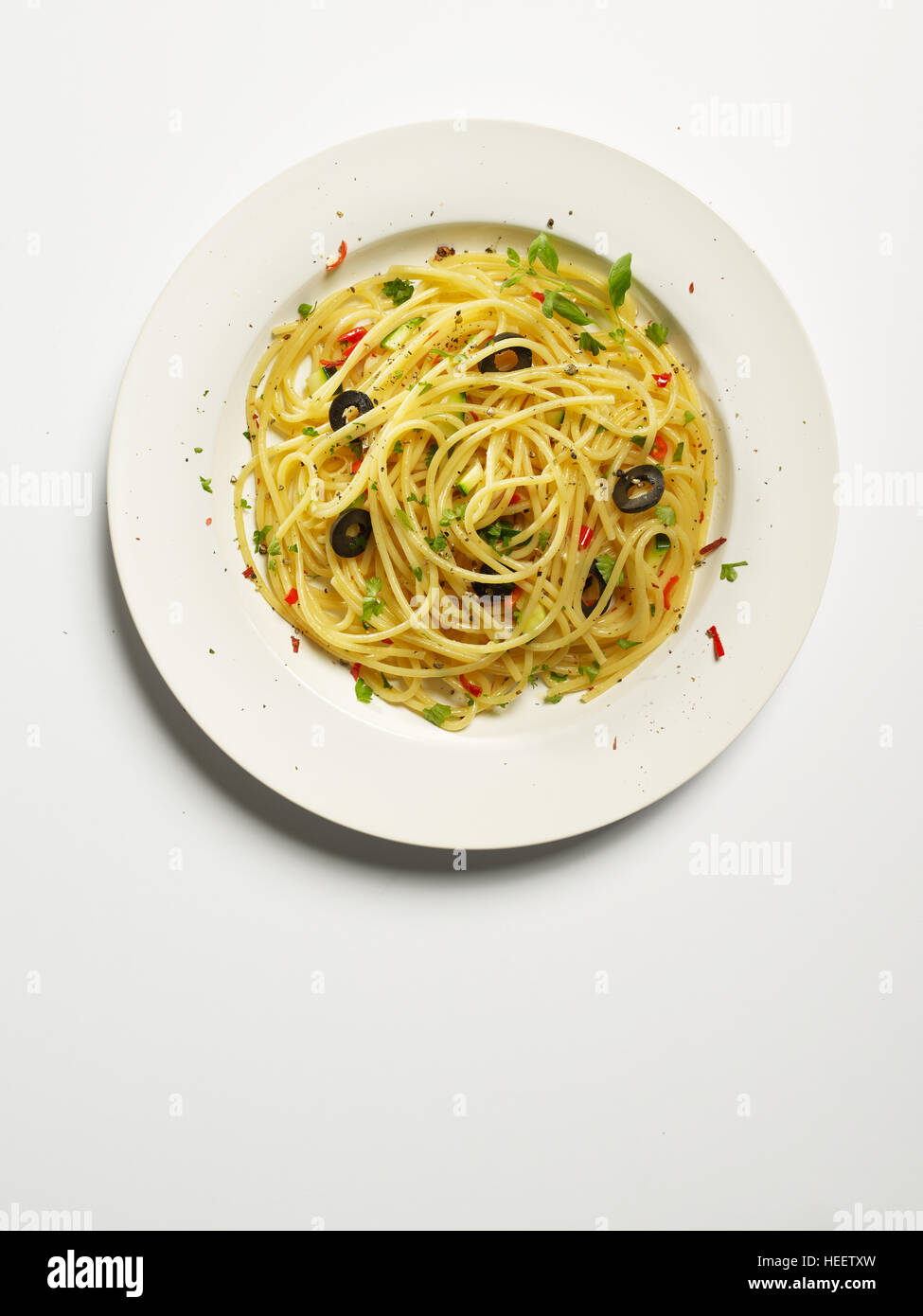 Spaghetti aglio, peperoni rossi, olio d'oliva, la zucchina, olive nere e prezzemolo sulla piastra bianca - pasta aglio olio e peperoncino Foto Stock