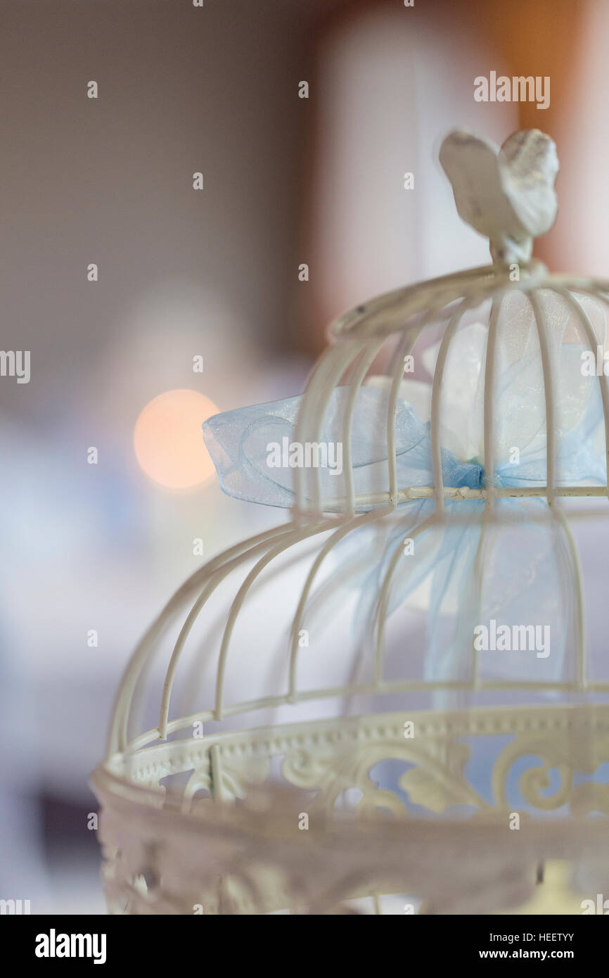 Vintage shabby chic avorio gabbia per uccelli con blue ribbon pura sparato contro bokeh pastello e illuminazione blu Foto Stock
