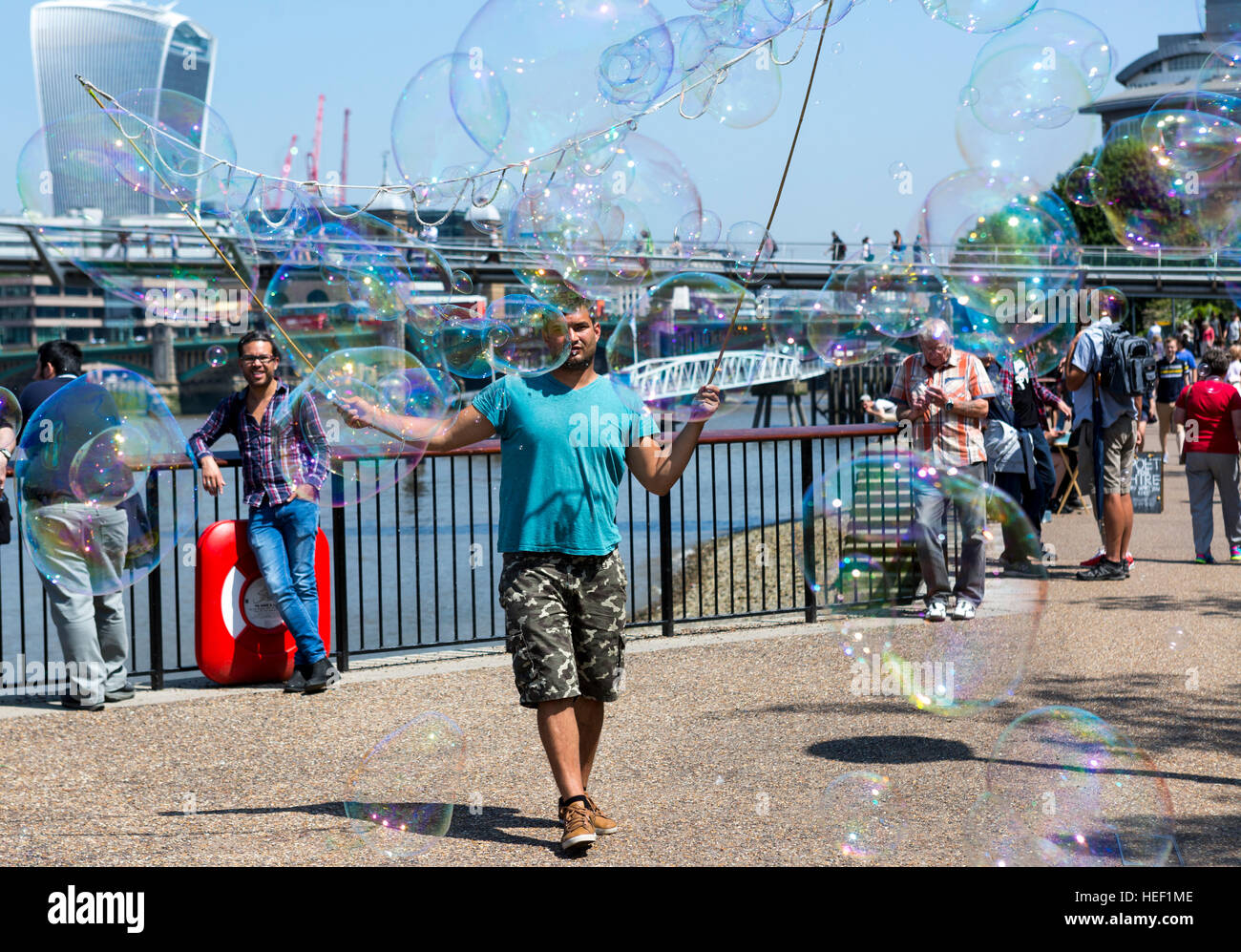 Un uomo che fa una vita da musicista di strada con grandi bolle di sapone sulla Southbank nel centro di Londra, Regno Unito Foto Stock