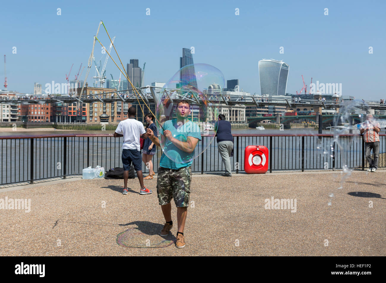 Un uomo musicista di strada per vivere con grande bolla di sapone sulla Southbank nel centro di Londra, Regno Unito Foto Stock