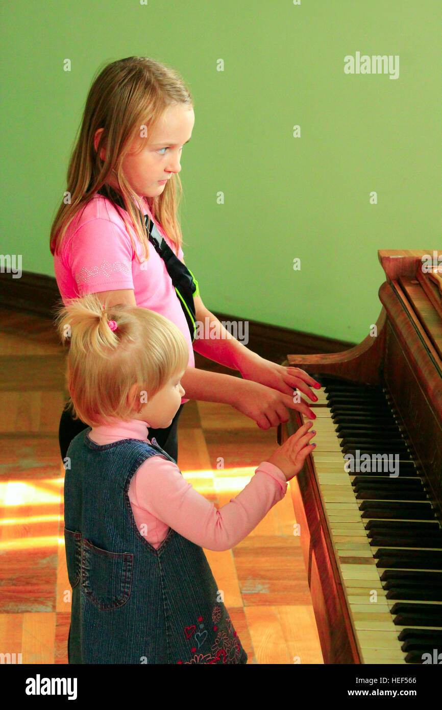 Poco belle ragazze sorelle suona il pianoforte Foto Stock