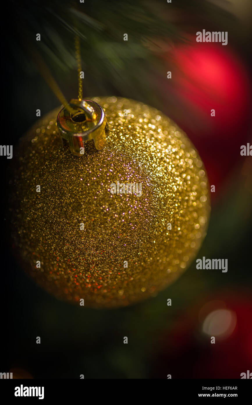 Rosso e oro baubles spiccano contro le luci scintillanti su un albero di Natale. Foto Stock