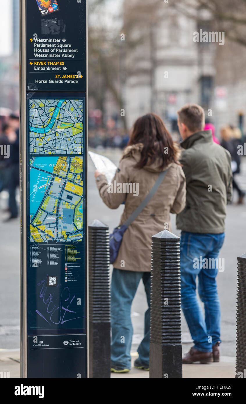 I turisti la consultazione di una mappa della città accanto a un trasporto per Londra leggibili London street map. Foto Stock