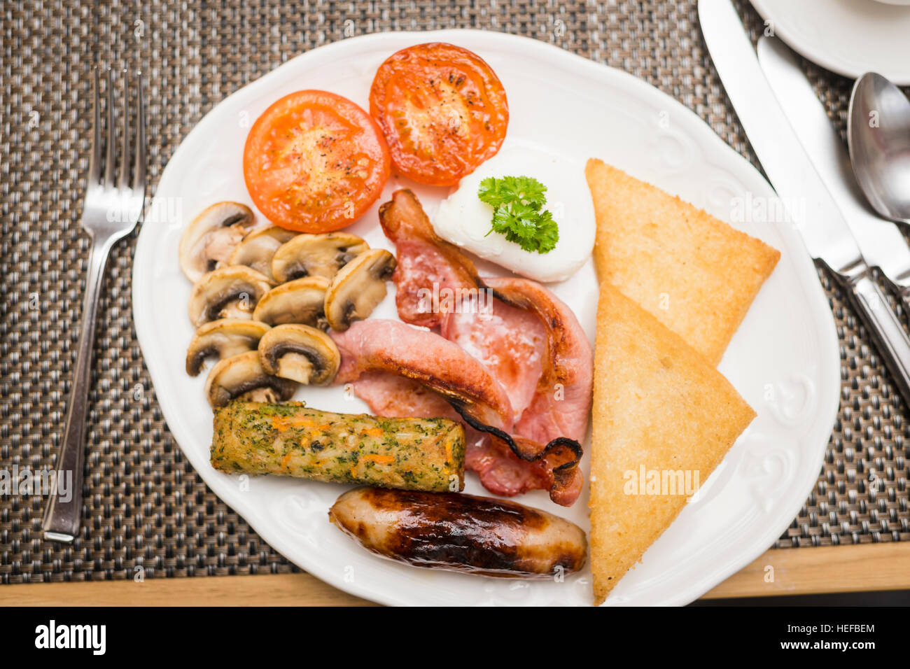 Full Monty: un fritto colazione inglese completa su una piastra bianca in un hotel del Regno Unito (pancetta, uova, salsicce, pomodori e funghi, pane fritto,) Foto Stock