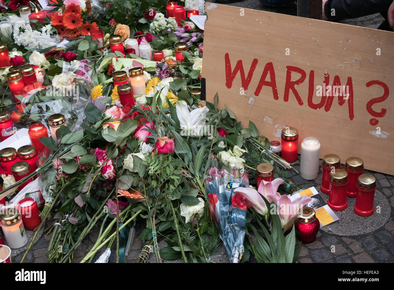 Candele, fiori e un segno con la parola tedesca "warum' (perché) Al Mercatino di Natale di Berlino, il giorno dopo l attacco terroristico Foto Stock