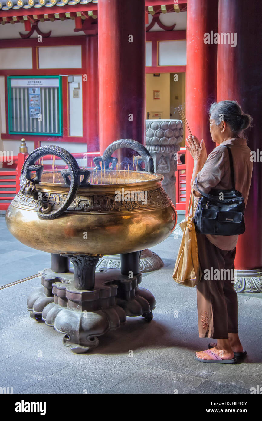 Donna asiatica pregando nel Dente del Buddha reliquia tempio in Chinatown, Singapore Foto Stock