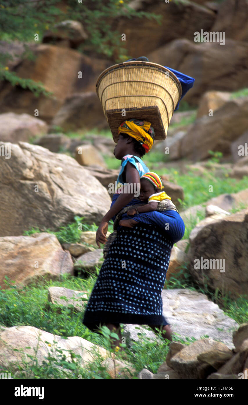 Ireli donna con il suo bambino sul retro e cesto di testa a testa, Paese Dogon del Mali Foto Stock
