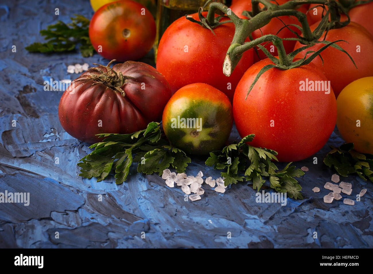 Pomodoro, il sale e il prezzemolo blu sullo sfondo di calcestruzzo. Messa a fuoco selettiva Foto Stock