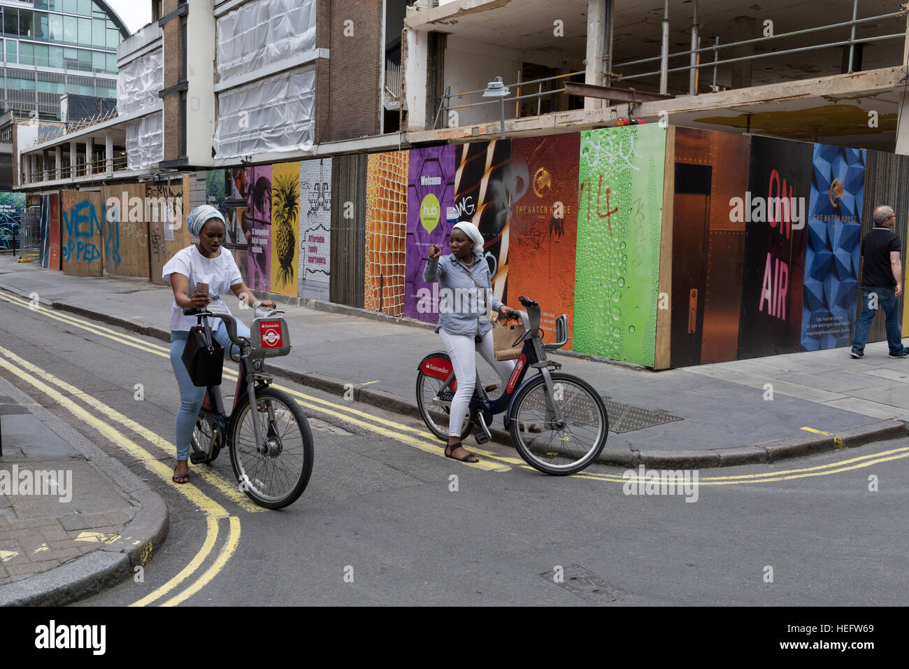 Due signore stop sul noleggio di biciclette in Soho di decidere dove andare avanti Foto Stock