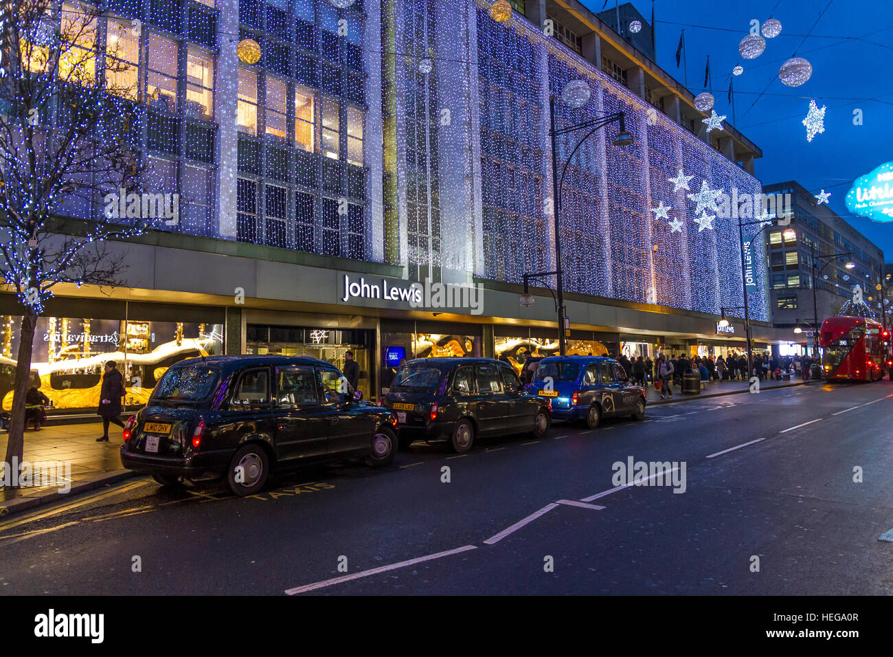 Una linea di taxi londinesi neri fuori dal John Lewis Department Store su Oxford St di Londra al tempo di Natale, Londra, Regno Unito Foto Stock