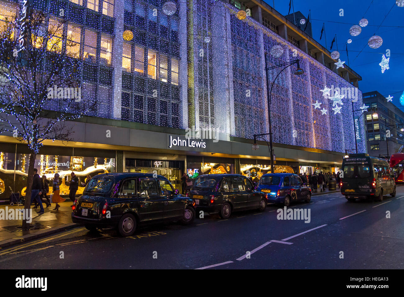 Una linea di taxi londinesi neri fuori dal John Lewis Department Store su Oxford St di Londra al tempo di Natale, Londra, Regno Unito Foto Stock