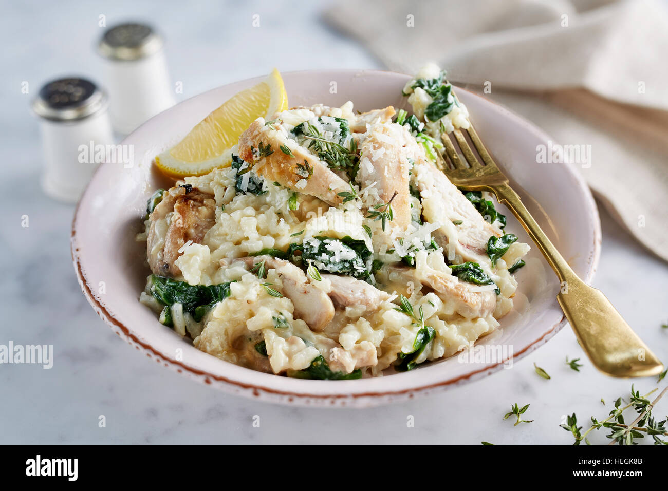 Risotto di pollo riso Arborio spinaci appassiti ciotola timo saporito brodo italiano Parmigiano formaggio Carnaroli Maratelli al dente burro Foto Stock