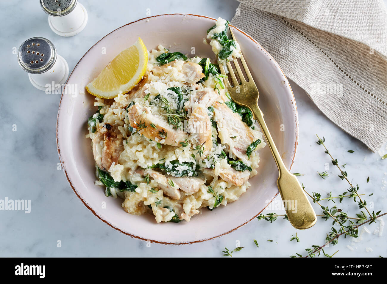 Risotto di pollo riso Arborio spinaci appassiti ciotola timo saporito brodo italiano Parmigiano formaggio Carnaroli Maratelli al dente burro Foto Stock