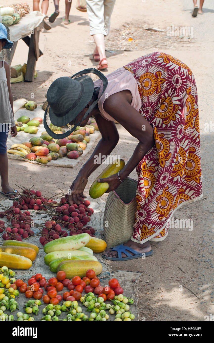 Stallo del mercato. La frutta e la verdura. Donna che fa una scelta dalla selezione. Mercato stradale. Sambava. Madagascar. Costa nord-orientale. Foto Stock