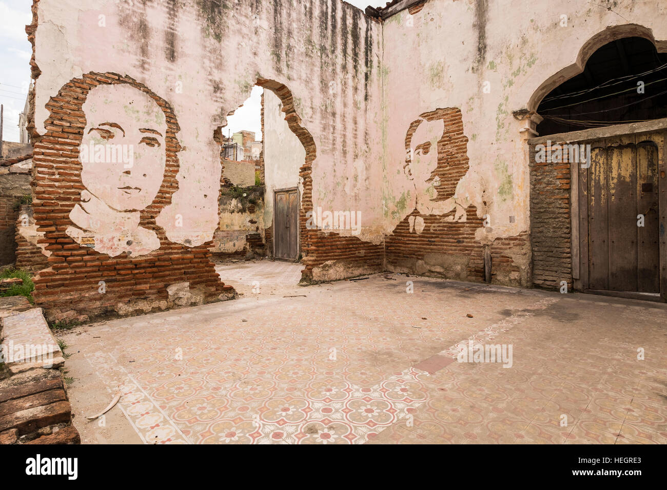 Facce tagliate in intonaco su un vecchio muro a Camaguey, Cuba Foto Stock