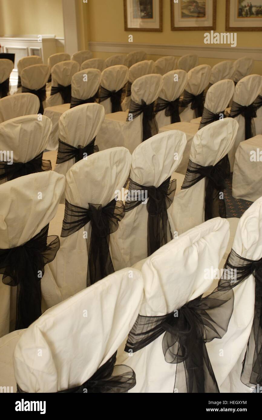 Una camera per un matrimonio civile cerimonia, sedie rivestita in tessuto bianco e legato con il grigio grigio archetti a nastro Foto Stock