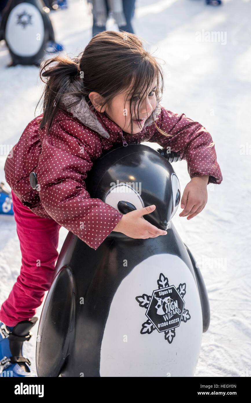 Giovani 3-5 anni asiatica, ragazzina musulmana divertirsi sulla pista di pattinaggio su ghiaccio in plastica con il supporto dei pinguini Foto Stock
