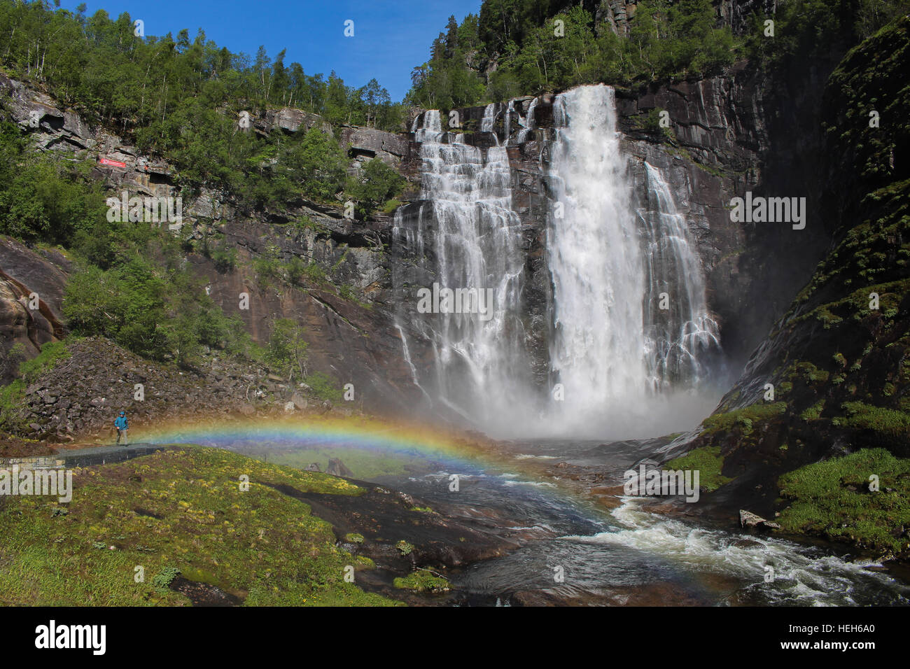 Un maschio di un escursionista in Norvegia con un arcobaleno e una cascata Foto Stock