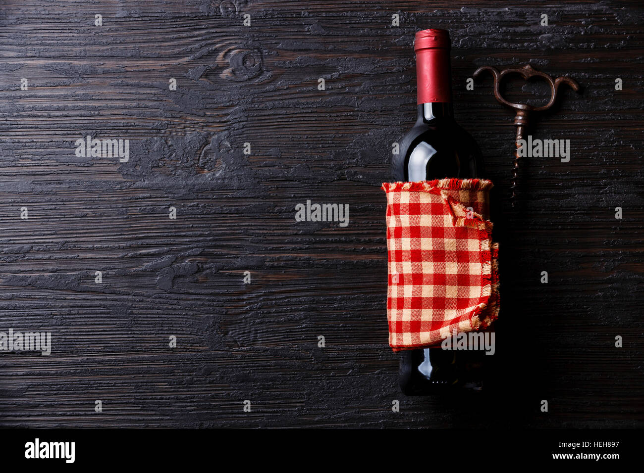 Bottiglia di vino e un cavatappi su nero di legno bruciato sfondo spazio di copia Foto Stock