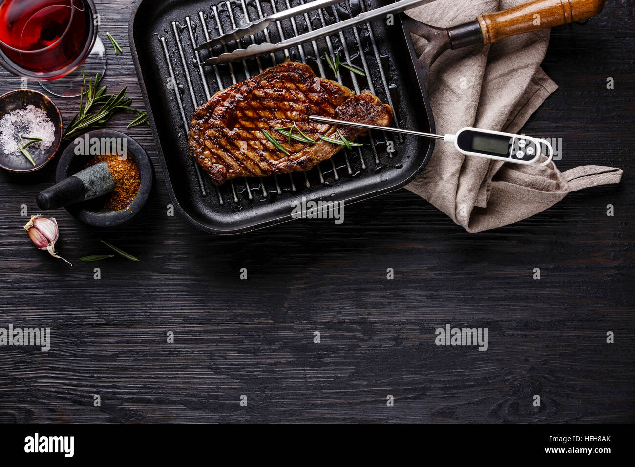 Bistecca alla griglia controfiletto in padella e il termometro della carne sul nero di legno bruciato sfondo spazio di copia Foto Stock