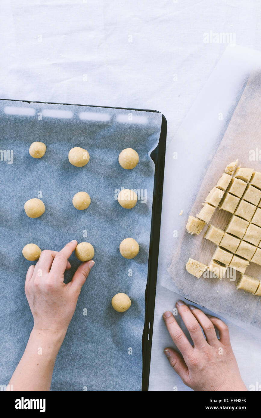 Ponendo le mani cookie di palline in una teglia da forno. Foto Stock