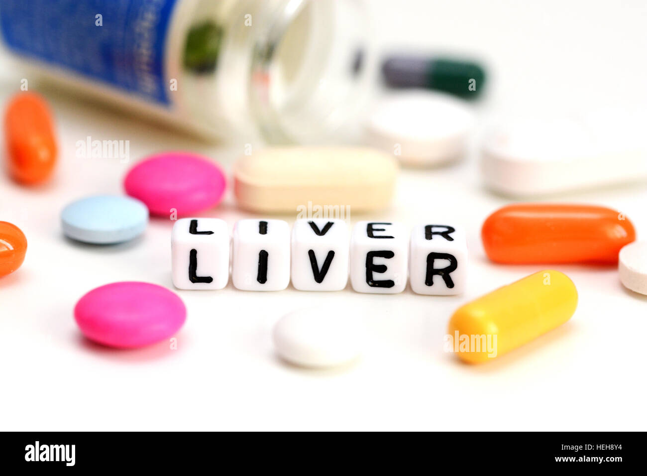 Problemi di fegato concetto con close-up di coloratissimi medical pillole e fegato parola su sfondo bianco Foto Stock