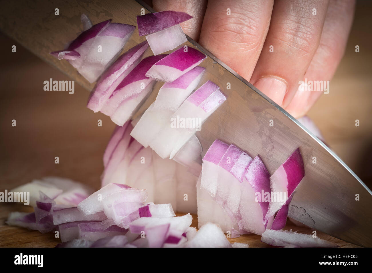 Lo Chef tritare una cipolla rossa con un coltello sul tagliere Foto Stock