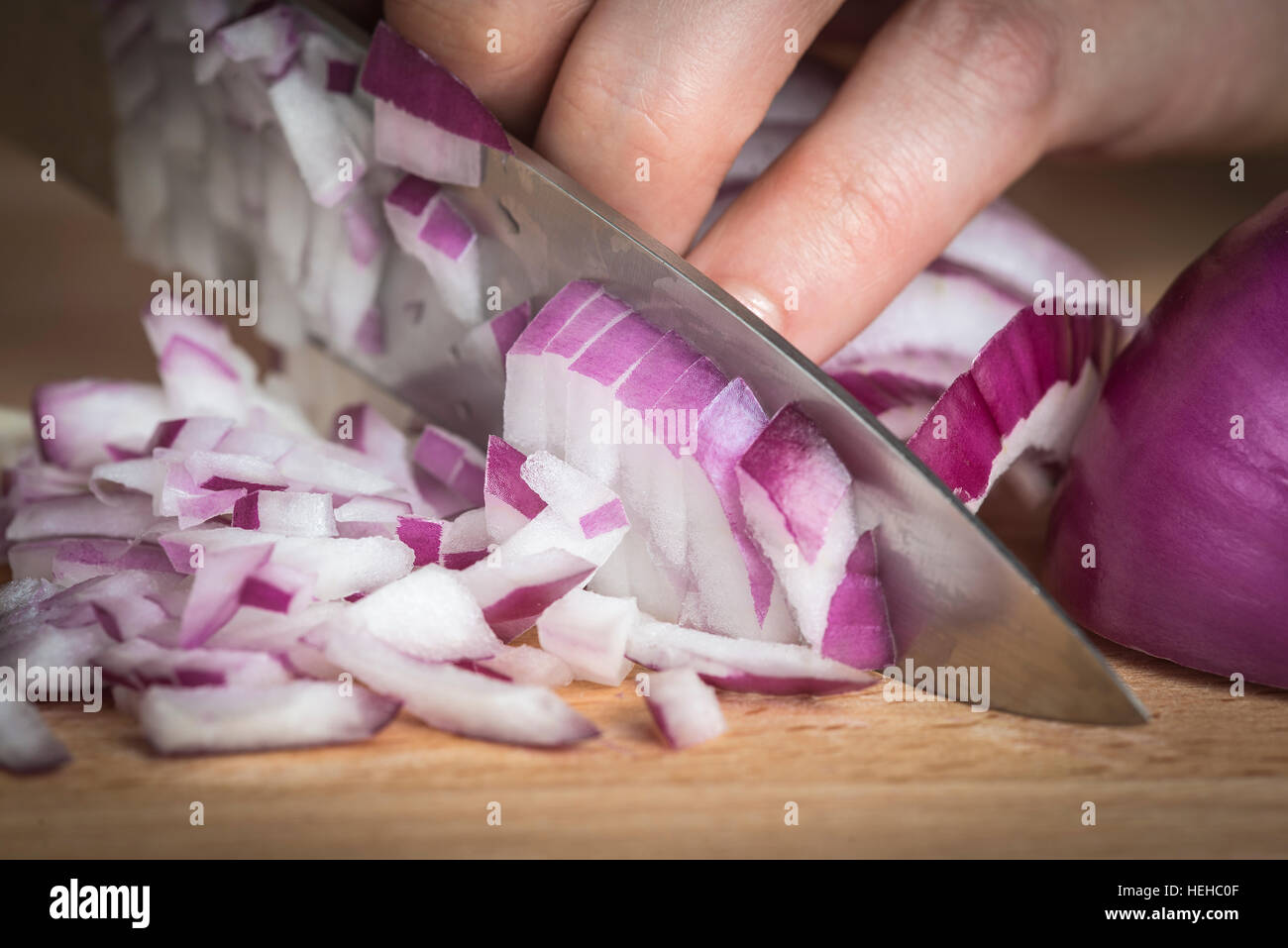 Lo Chef tritare una cipolla rossa con un coltello sul tagliere Foto Stock