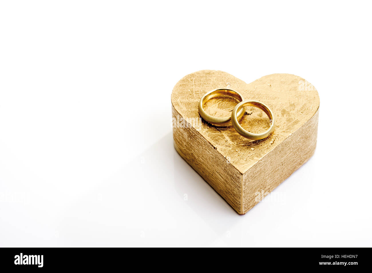 Gli anelli di nozze, bande su un cuore a forma di cartone dorato confezione regalo Foto Stock