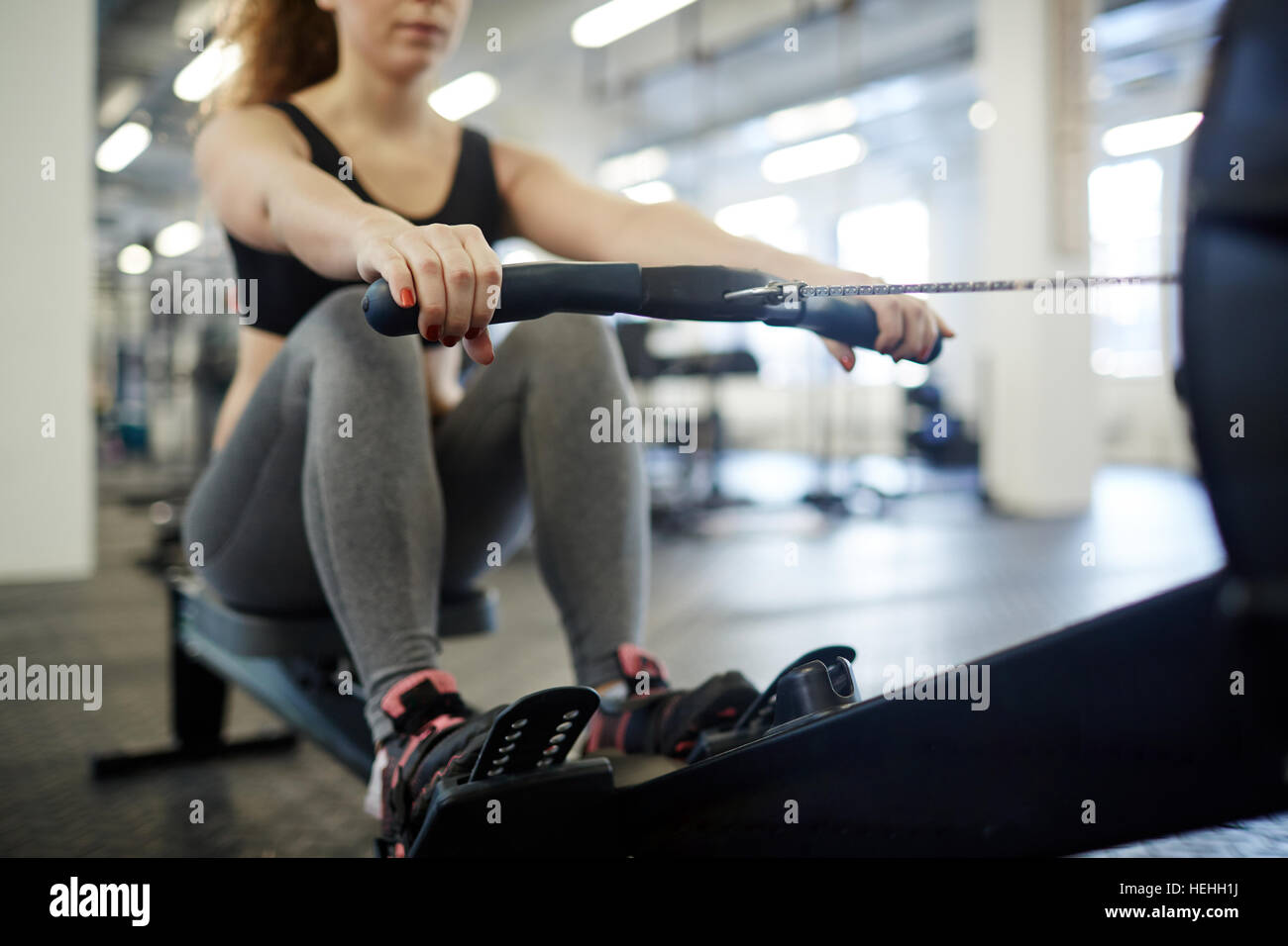 Giovane donna training su canottaggio-macchina in palestra Foto Stock