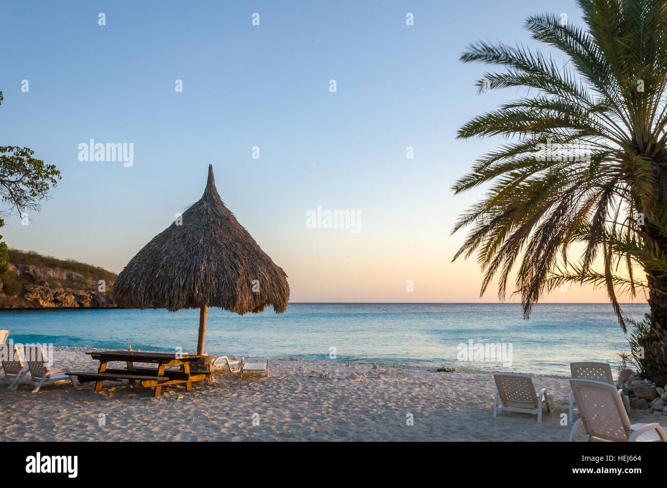 Tramonto sulla spiaggia in Curacao isola dei Caraibi. Spiaggia Bianca, cielo blu e blu cristallino dell'acqua. Spiaggia di sabbia coperte con milioni di frammenti di conchiglie. Foto Stock