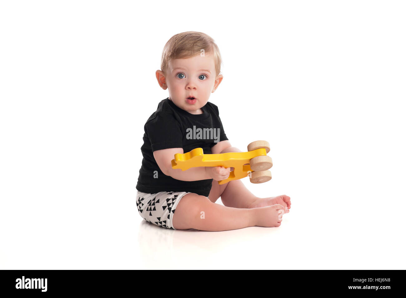 Un otto mesi baby boy giocare con un giocattolo di legno. Isolato su uno sfondo bianco. Foto Stock
