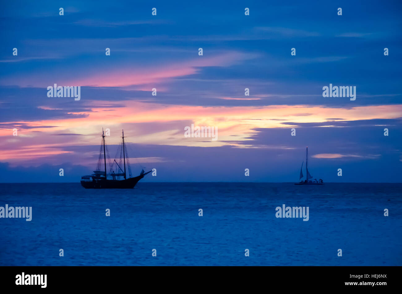 Pirate barca a vela sul mare navigando verso il tramonto. L'immagine è stata presa da Palm Beach di Aruba, nel mar dei Caraibi. Foto Stock