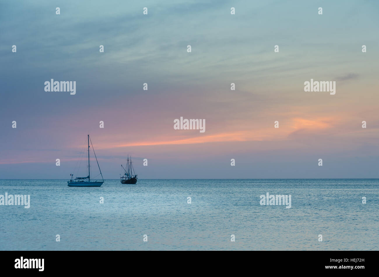 Barche a vela in mare la navigazione sotto il tramonto. L'immagine è stata presa da Palm Beach di Aruba, nel mar dei Caraibi. Foto Stock