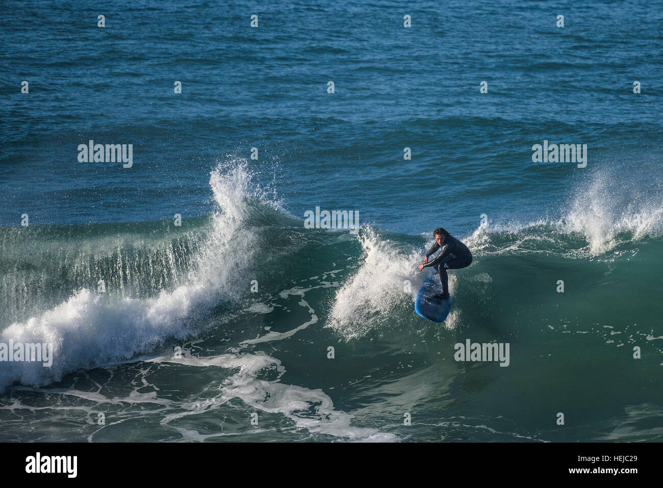 Un surfista cavalca un big wave a poco Fistral in Newquay; Cornovaglia Foto Stock