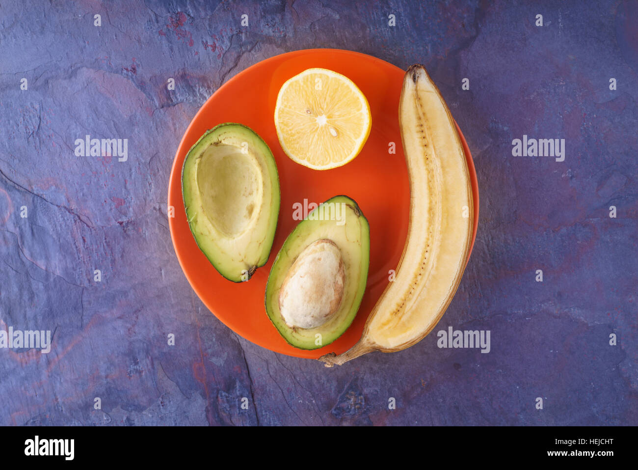 Frutti tropicali sulla piastra di colore arancione su sfondo blu orizzontale Foto Stock