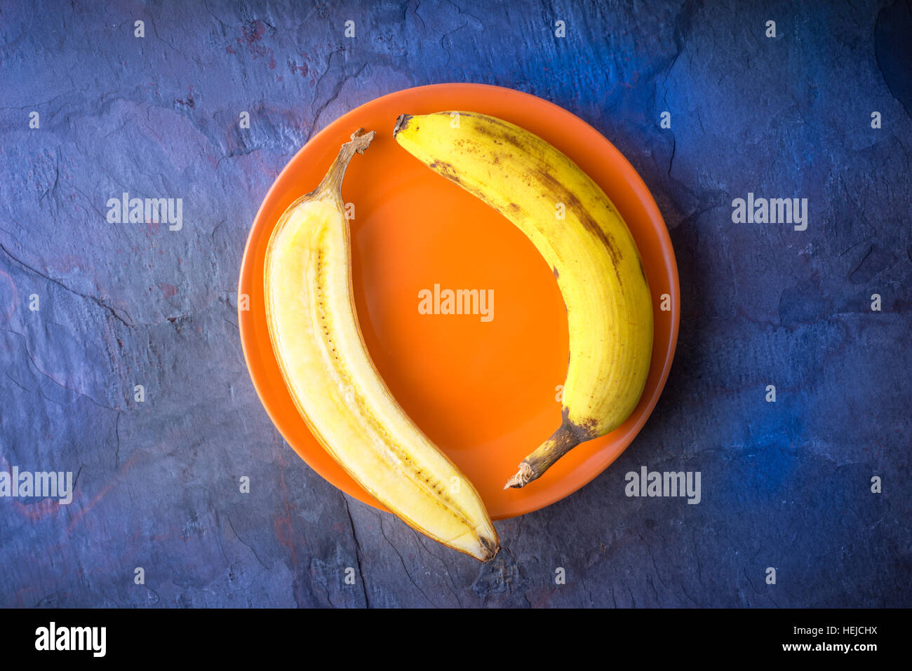 Mezza banana giace su un arancio piastra in orizzontale Foto Stock