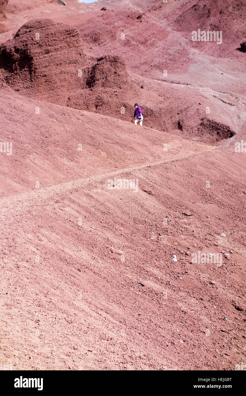 Un turista segue un percorso fino a una scogliera composta o Rossi lapilli frammenti, El Golfo, Lanzarote, Isole canarie, Spagna Foto Stock