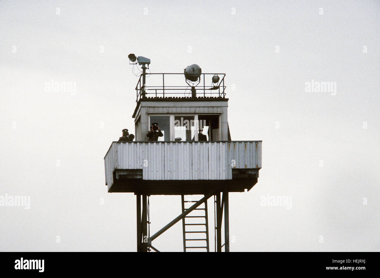 Le guardie di frontiera della Germania Est monitorano il confine tra la Germania Est e la Germania Ovest da una torre di guardia, mantenendo la sicurezza e la sorveglianza durante il periodo della Guerra fredda. Foto Stock